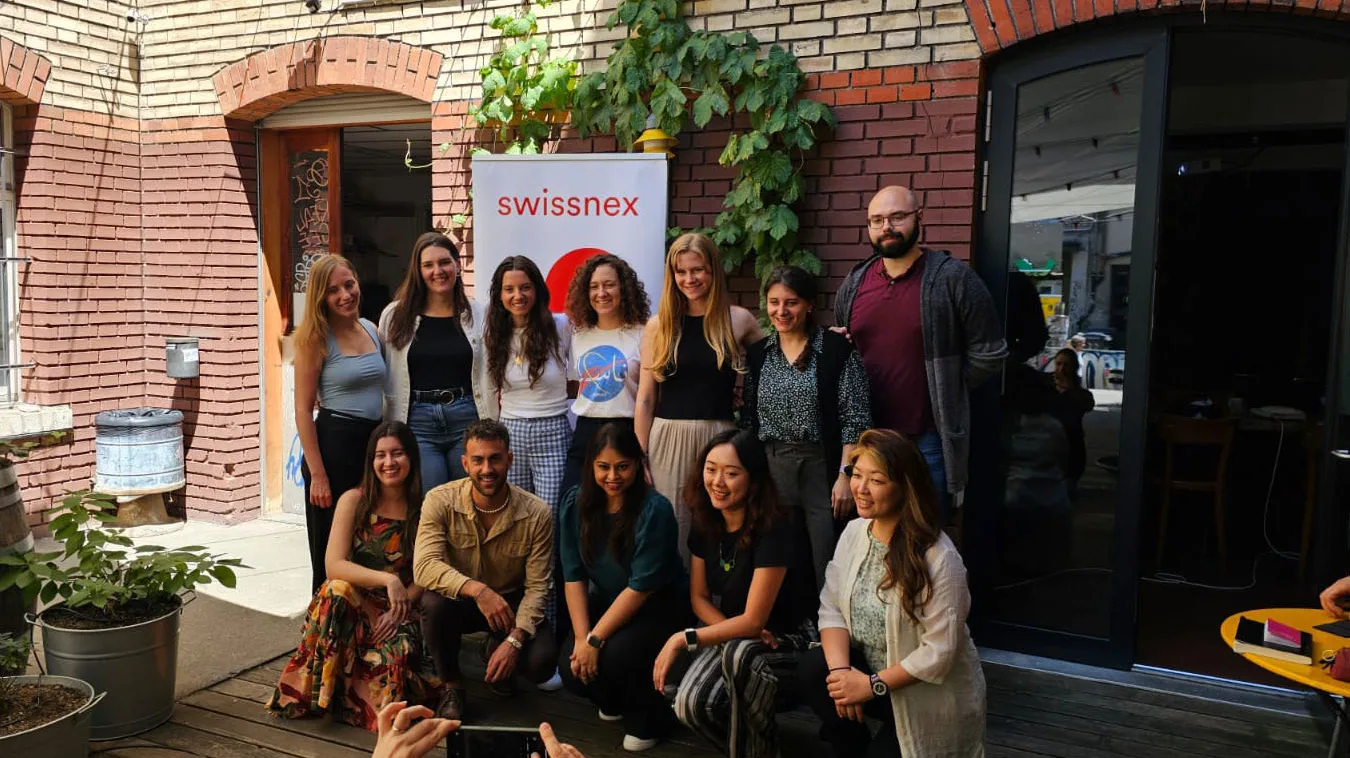 Internationalisation Camps A group of people pose for a picture in a courtyard in front of a brick wall and a Swissnex banner.